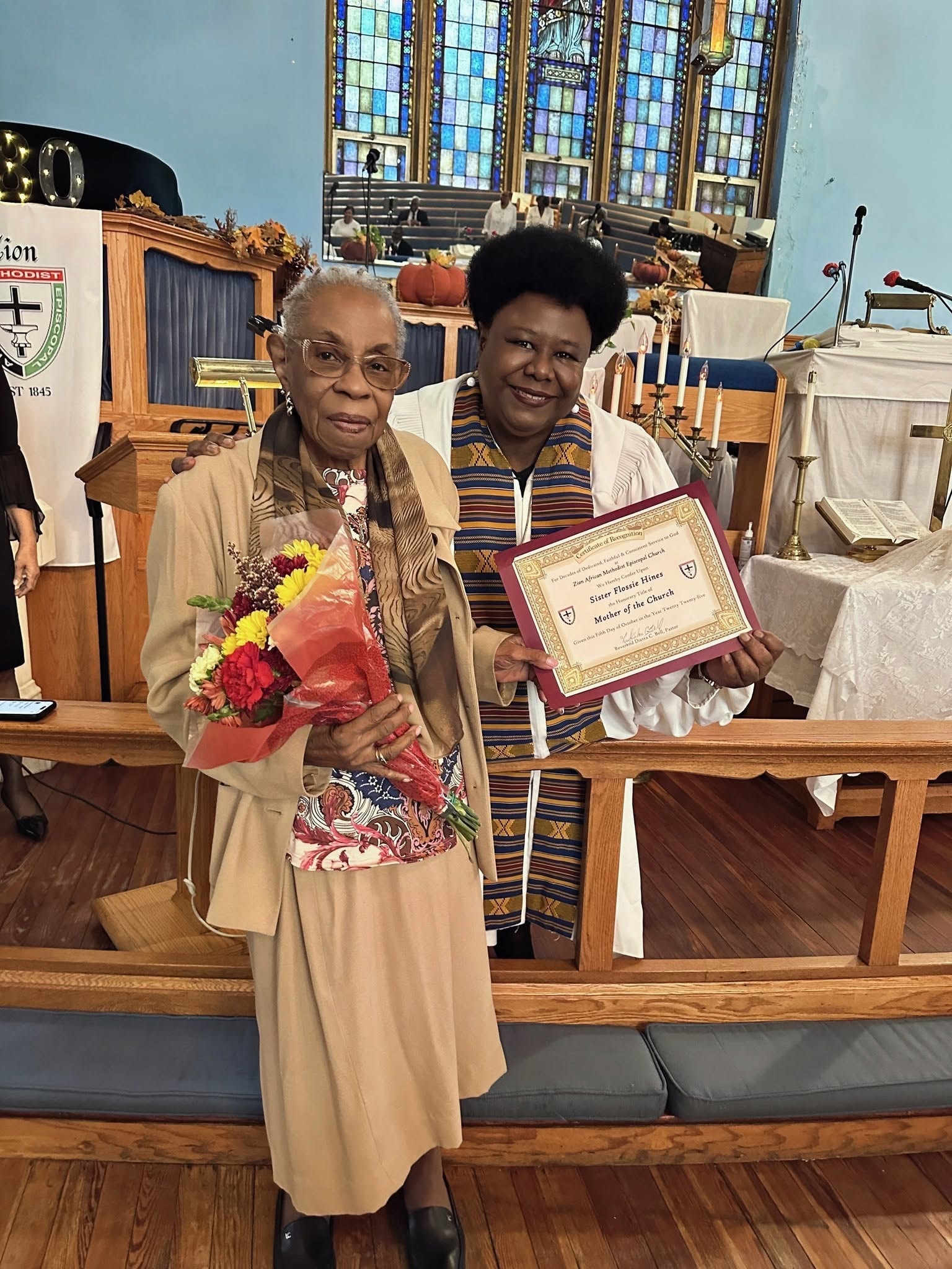 Pastor Bell presenting Sister Flossie Hines with the Mother of the Church recognition certificate at Zion AME Church