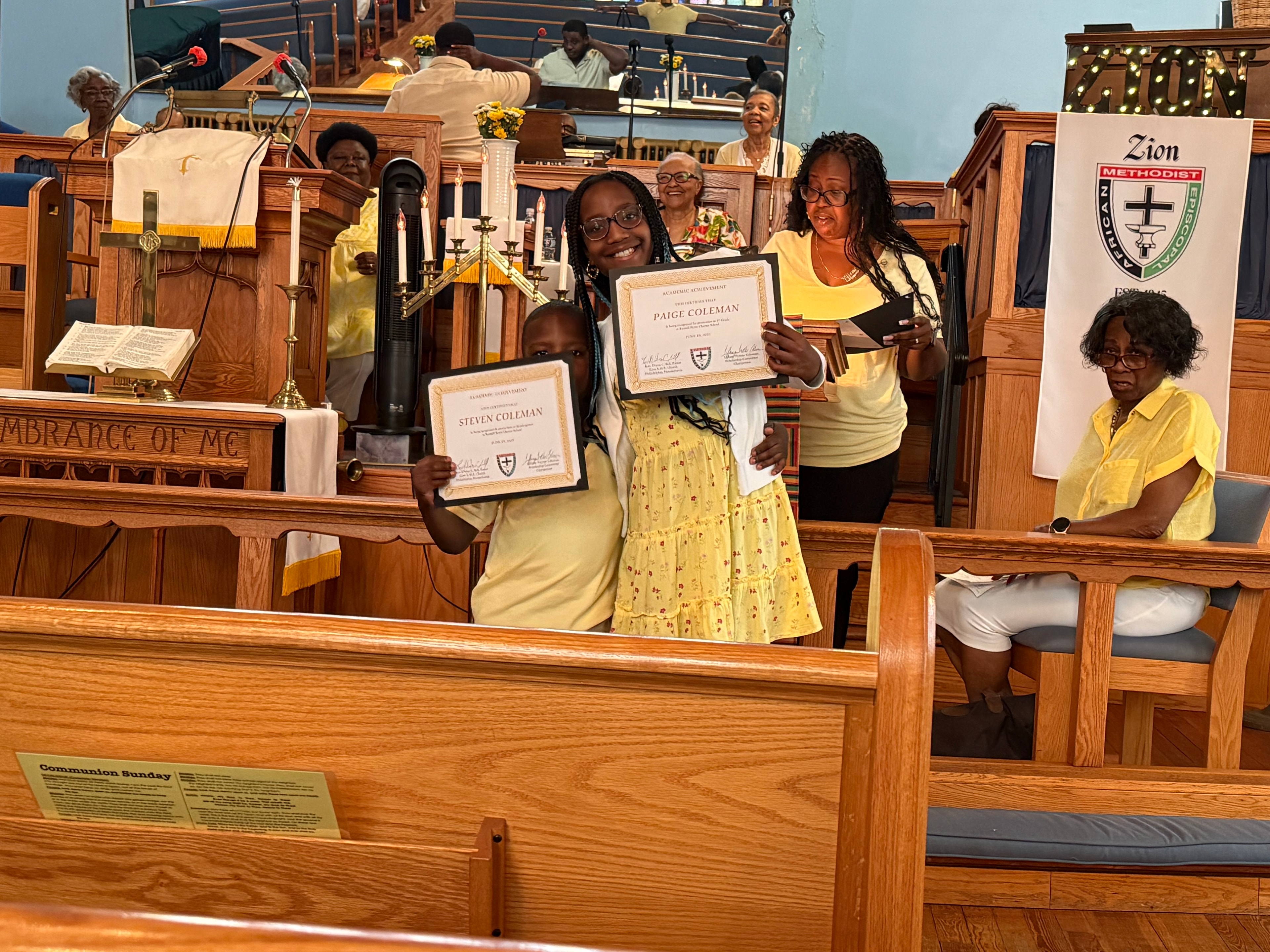 Children proudly displaying their academic achievement certificates at Zion AME Church